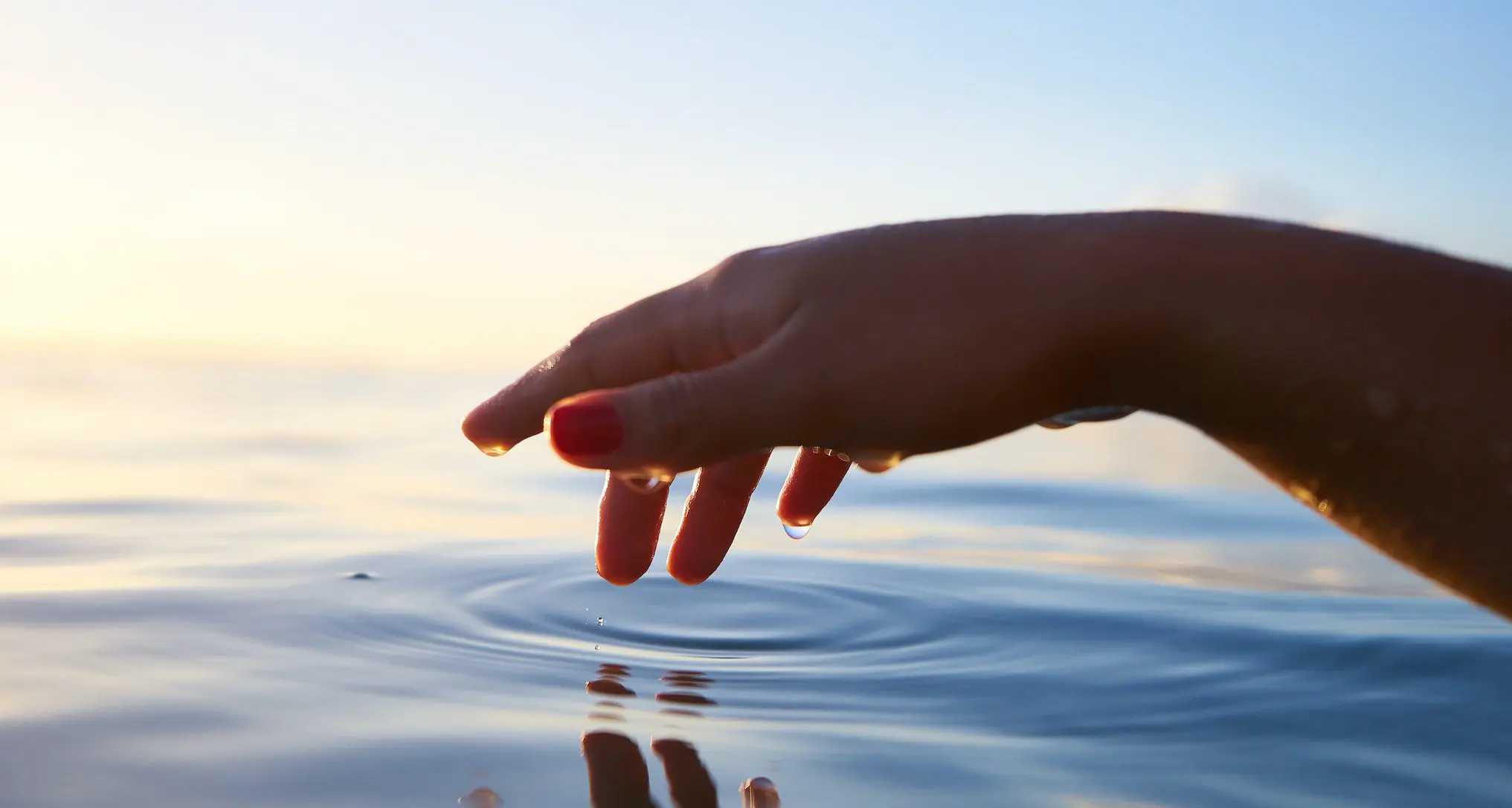 hand skimming over water