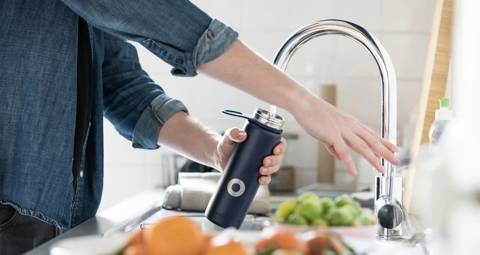 woman filling water bottle from sink