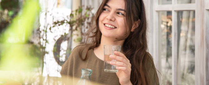 Attractive woman drinks water with lemon