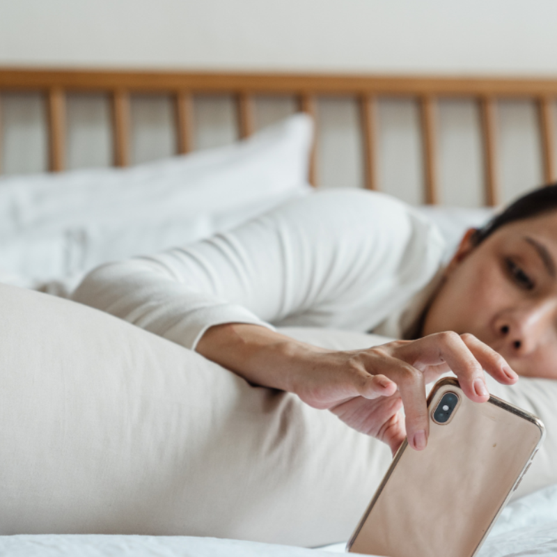 a woman lies on a bed looking at phone