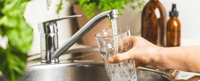 person filling up a glass of water from the tap