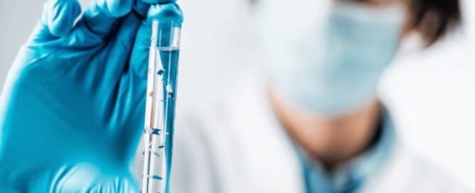 Scientist observing microplastics in water beaker