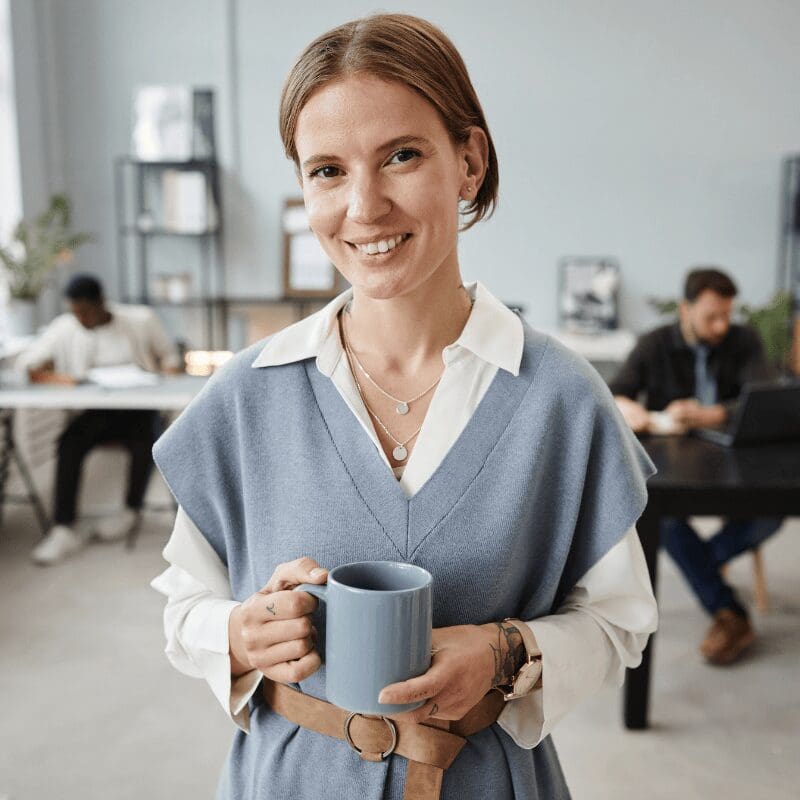 businesswoman-drinking-coffee-at-office-2023 (1) business woman smiling and drinking coffee