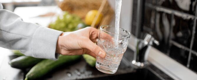 person filling up their water glass at the tap