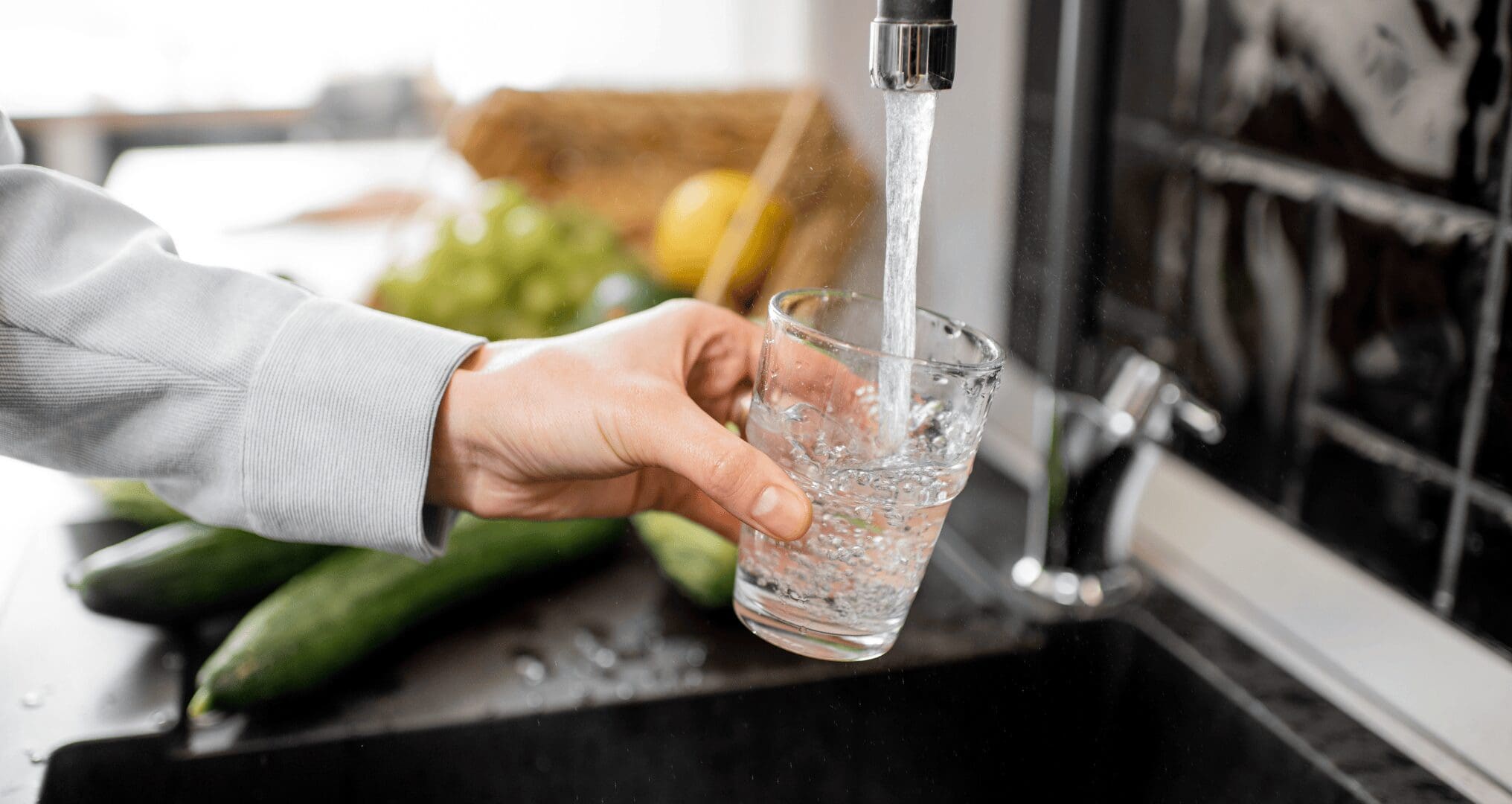 person filling up their water glass at the tap