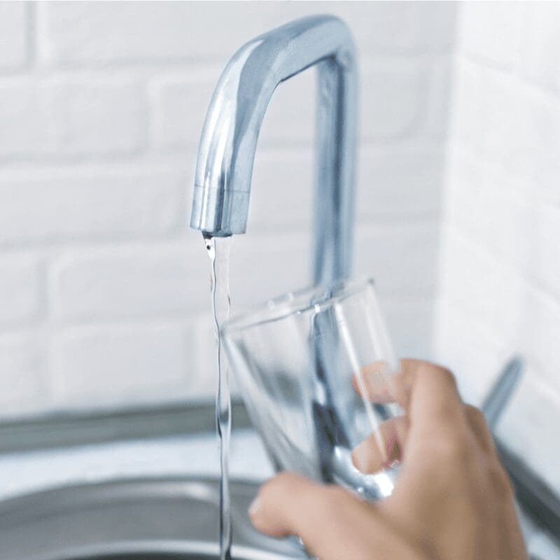 person filling up glass with tap water