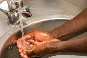 man washing his hands with tap water