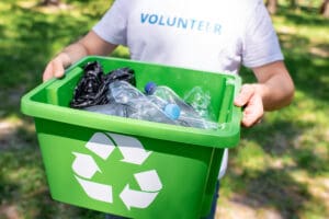 volunteer man holding a recycling bin full of bottles
