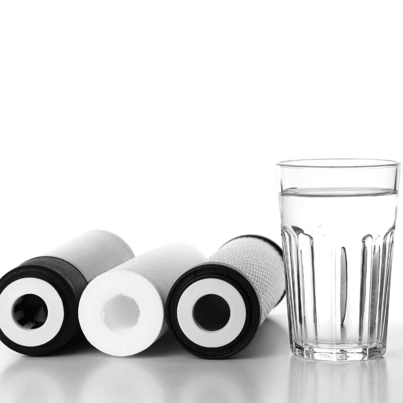 three water filter cartridges and glass of water