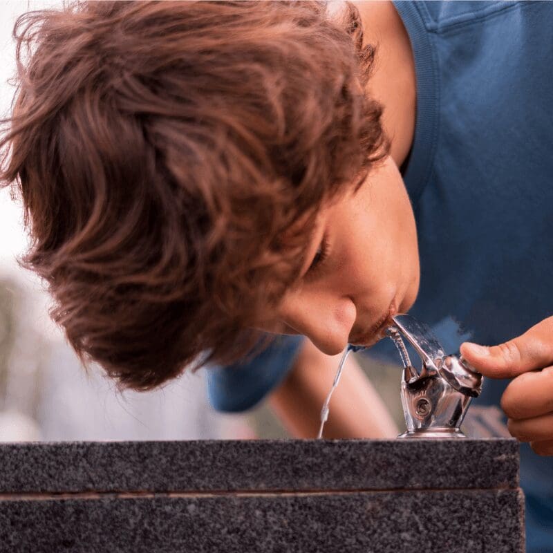 young-man-feel-thirsty-drinking-water-from-public young man getting drink from public water drinking fountain