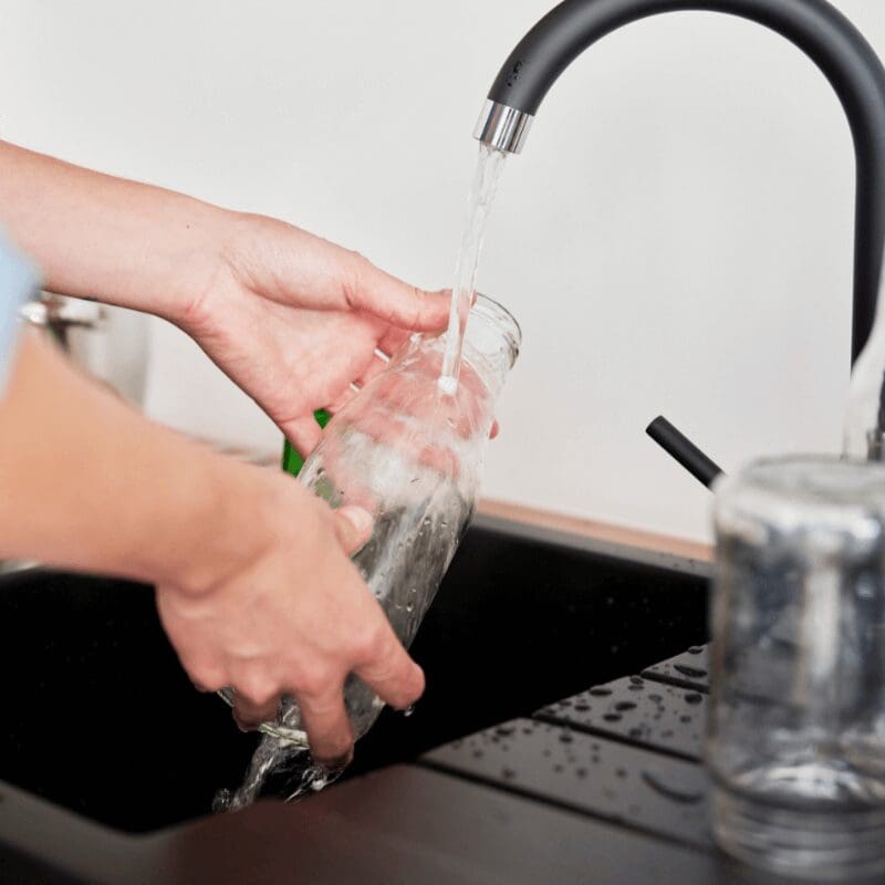 close-up of woman rinsing bottle in sink